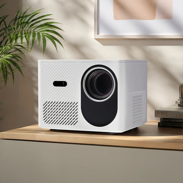 White projector on a wooden surface with a plant in the background